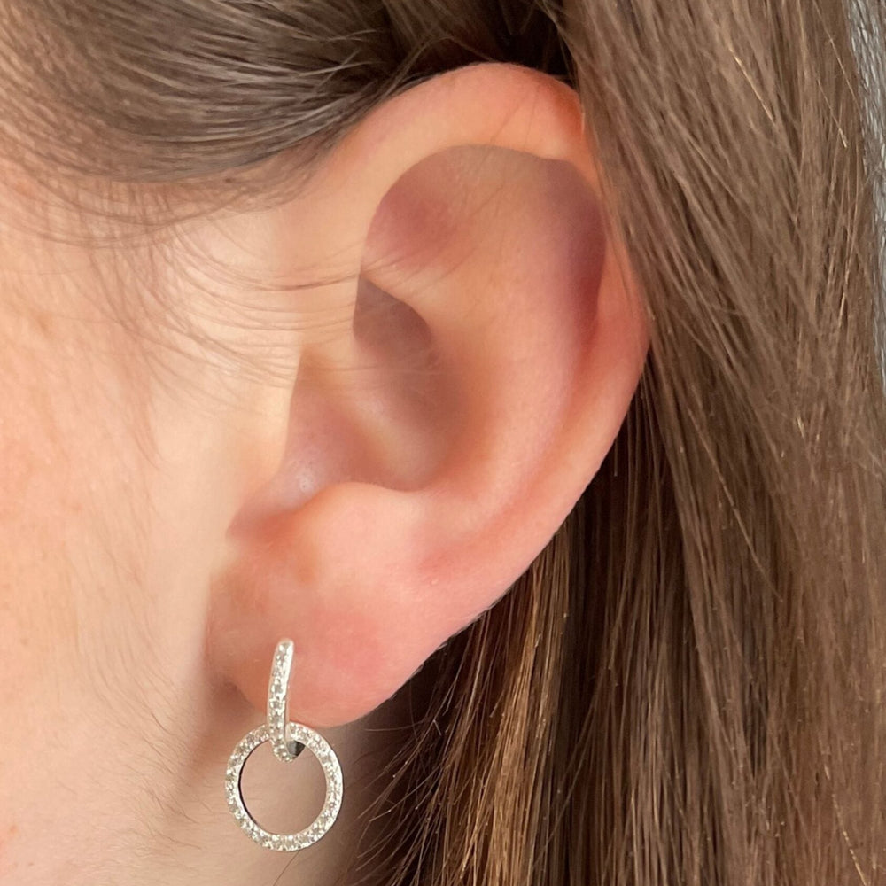 
                  
                    close up model wearing cz silver circle charm huggies
                  
                