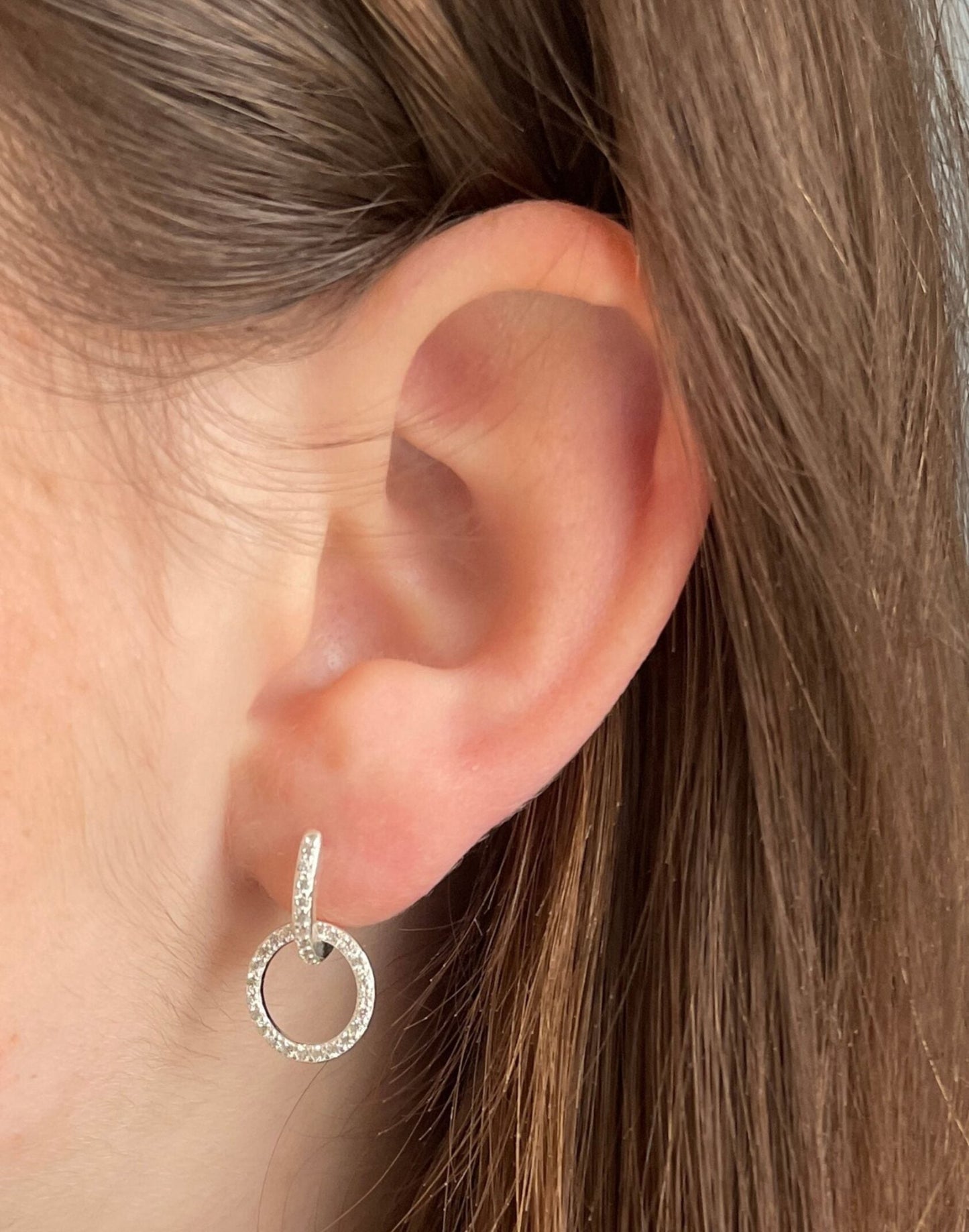 close up model wearing cz silver circle charm huggies