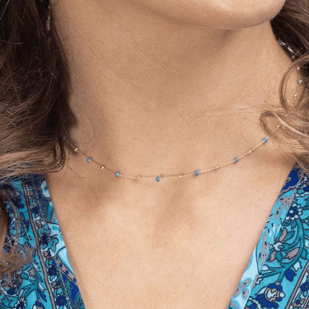 
                  
                    close up of model wearing gold dark turquoise enamel necklace
                  
                