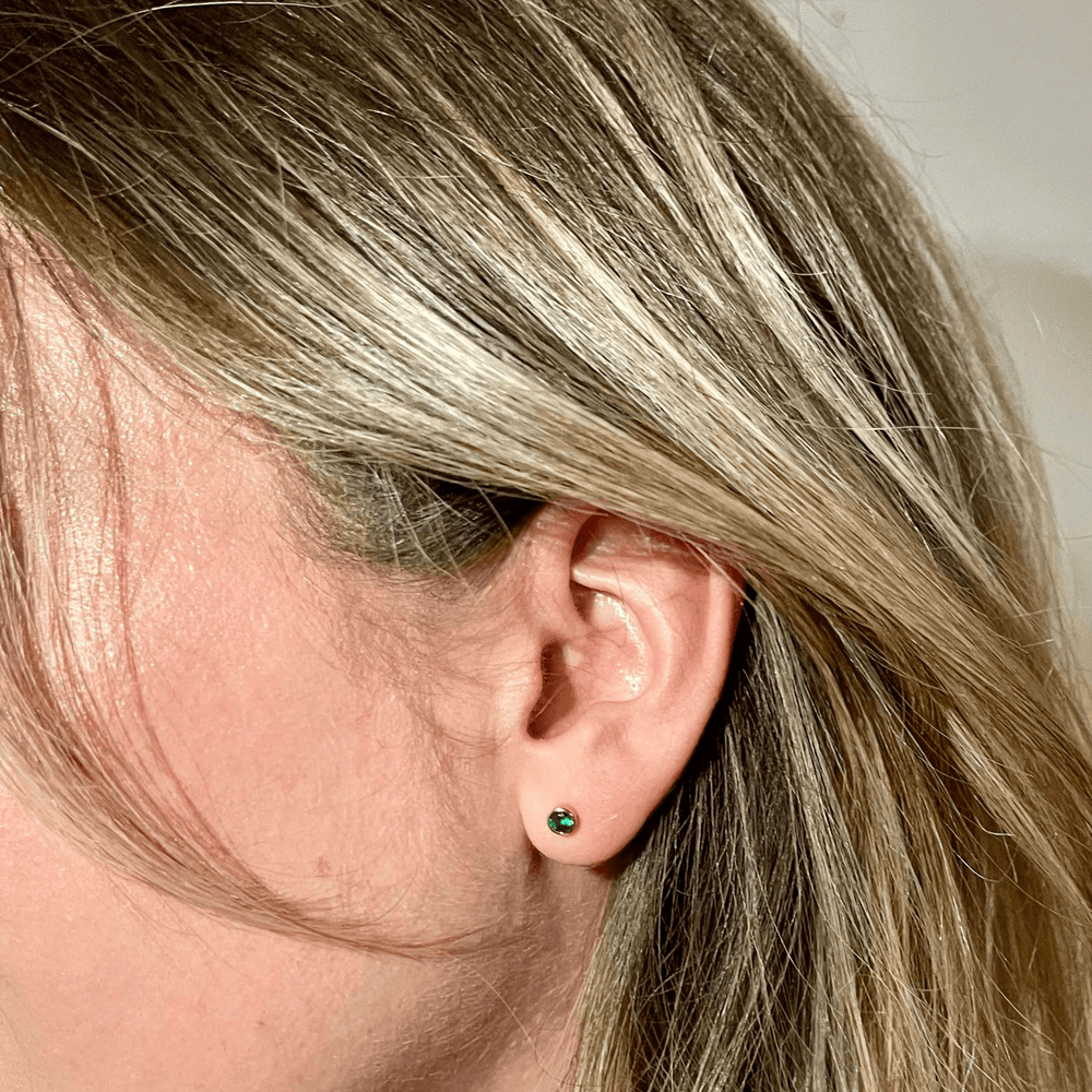 
                  
                    green coloured birthstone studs in model's ear
                  
                