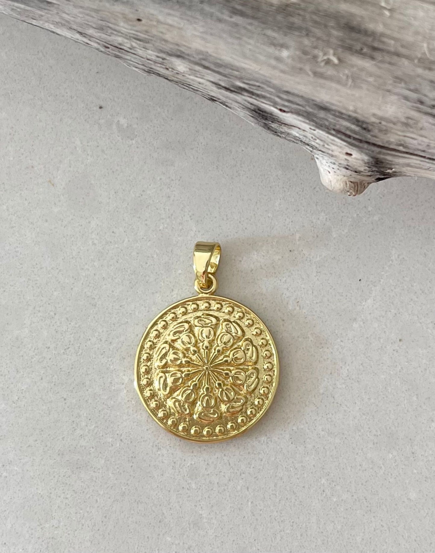 Gold Fill disc pendant on a pale tile