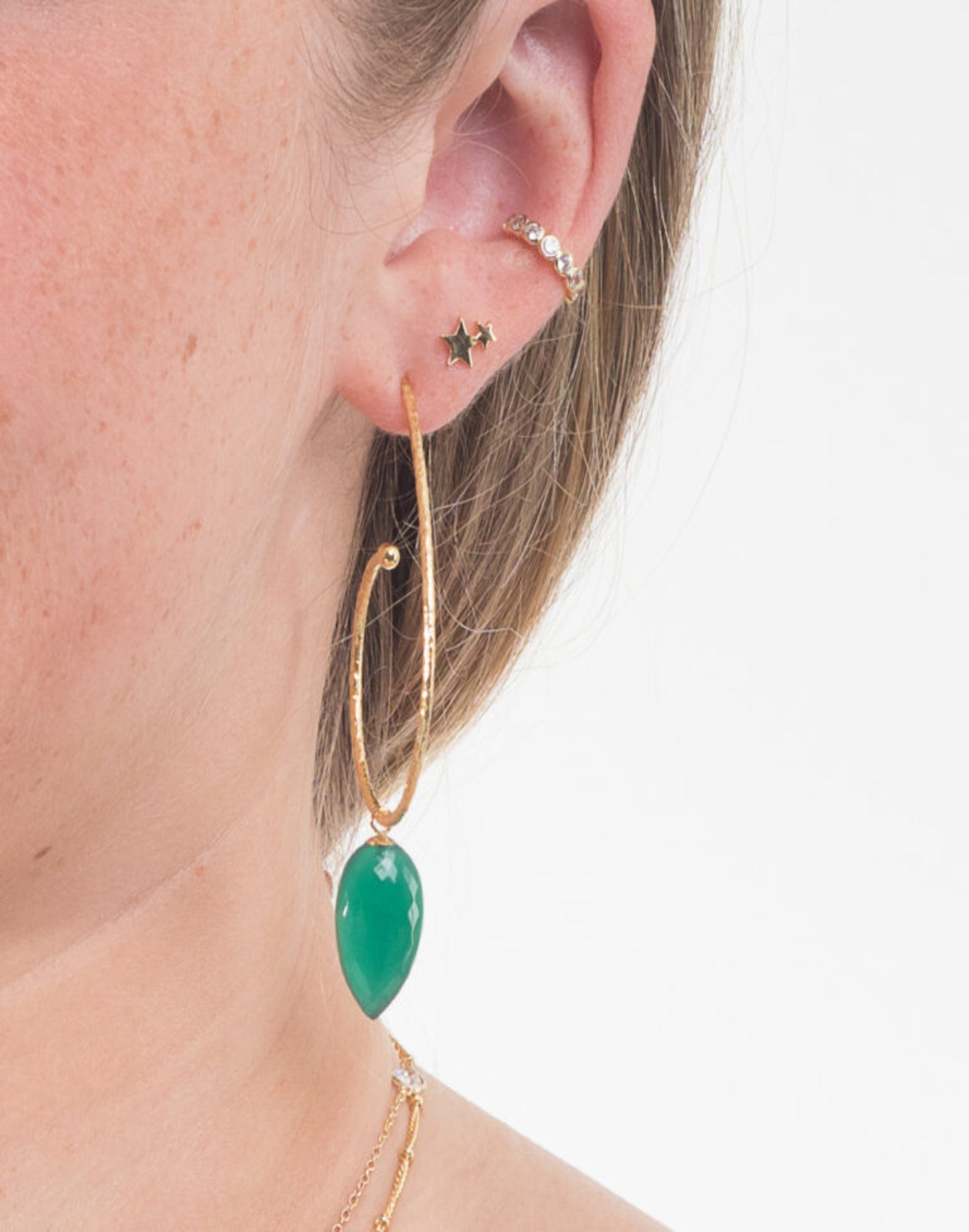 model wears large gold hoop with gree onyx drop in ear