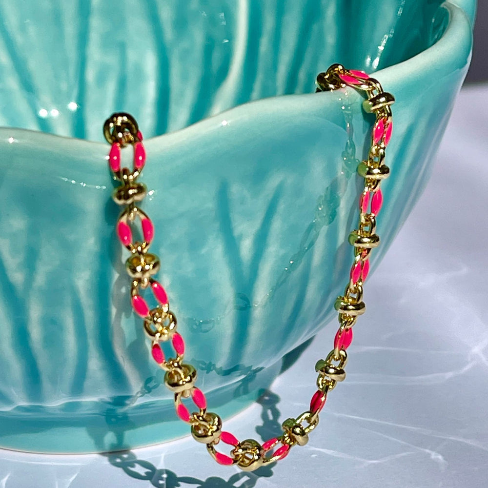 
                  
                    Pink enamel bracelet draped over a teal coloured bowl
                  
                