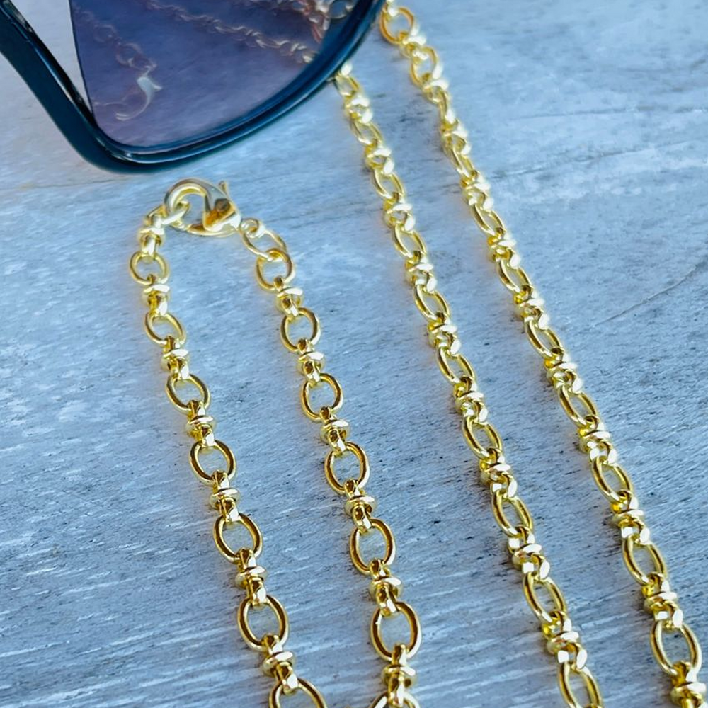 
                  
                    Pippa gold link bracelet and necklace on a textured surface with sunglasses in the background
                  
                