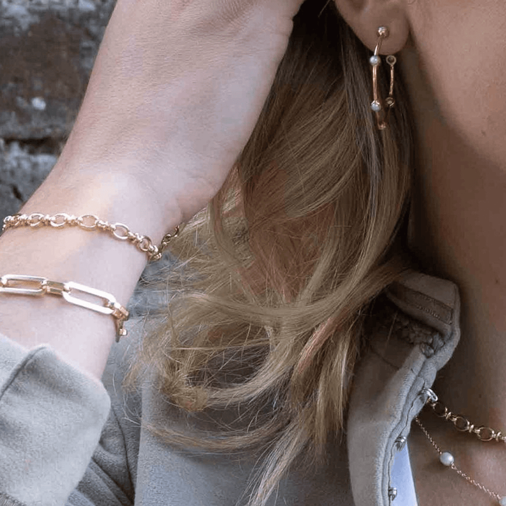 
                  
                    Close-up of a person wearing pippa gold link bracelet jewellery with earrings and necklaces
                  
                