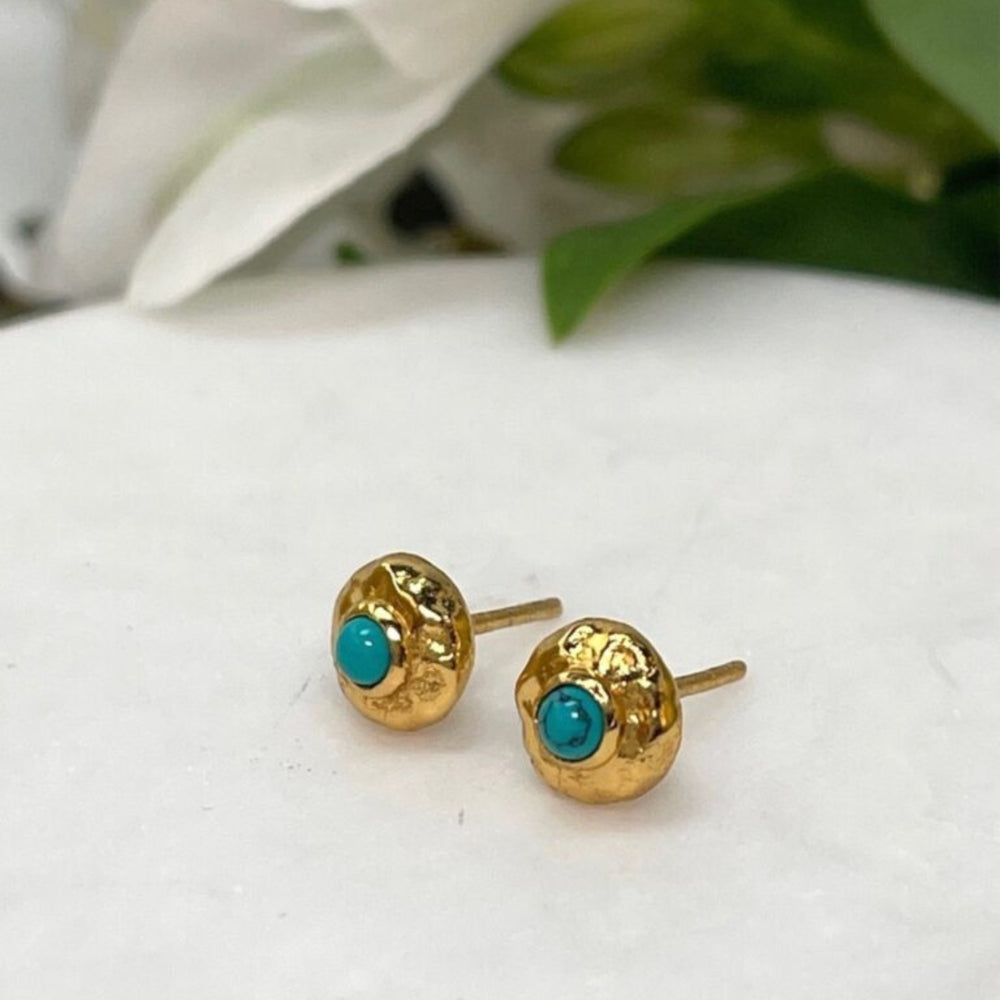 turquoise and gold stud earrings on tile