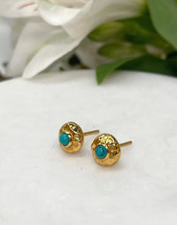 turquoise and gold stud earrings on tile